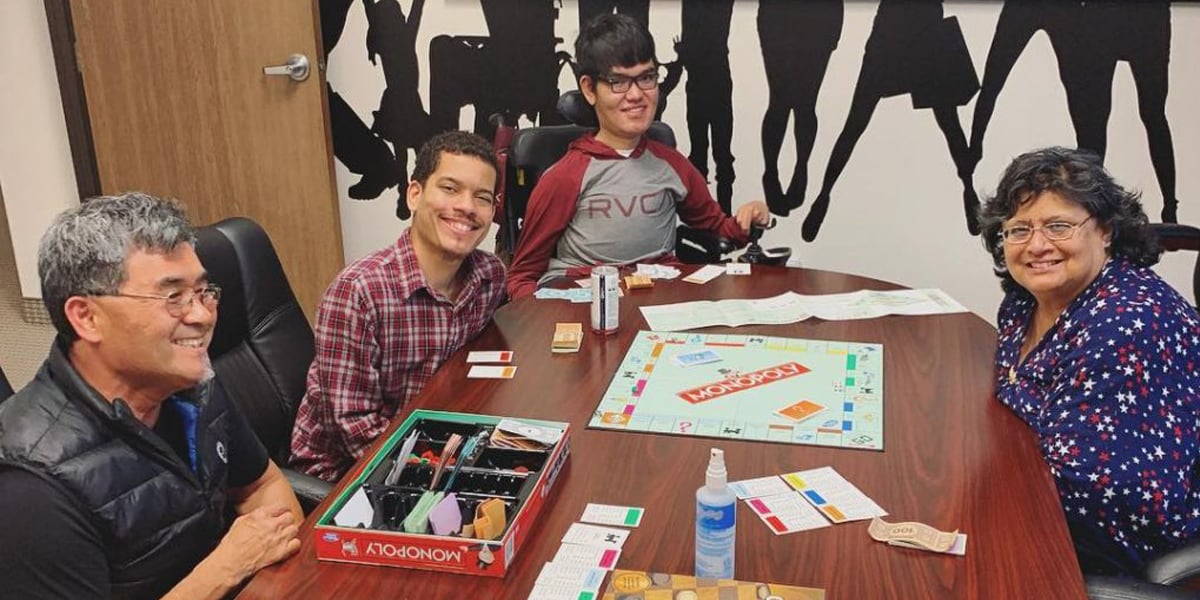 Young consumers smile for a photo as they play a game of Monopoly at one of the RSI game days in the San Bernardino office.