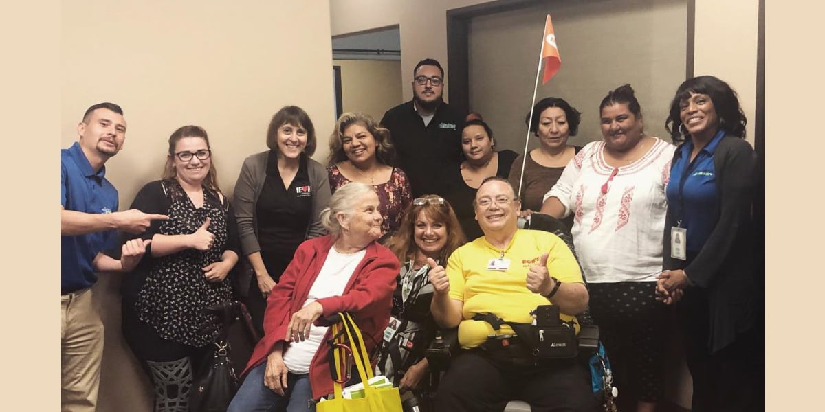 A large group of consumers and staff members gather for a photo after completing a Living Well in the Community course at the San Bernardino office