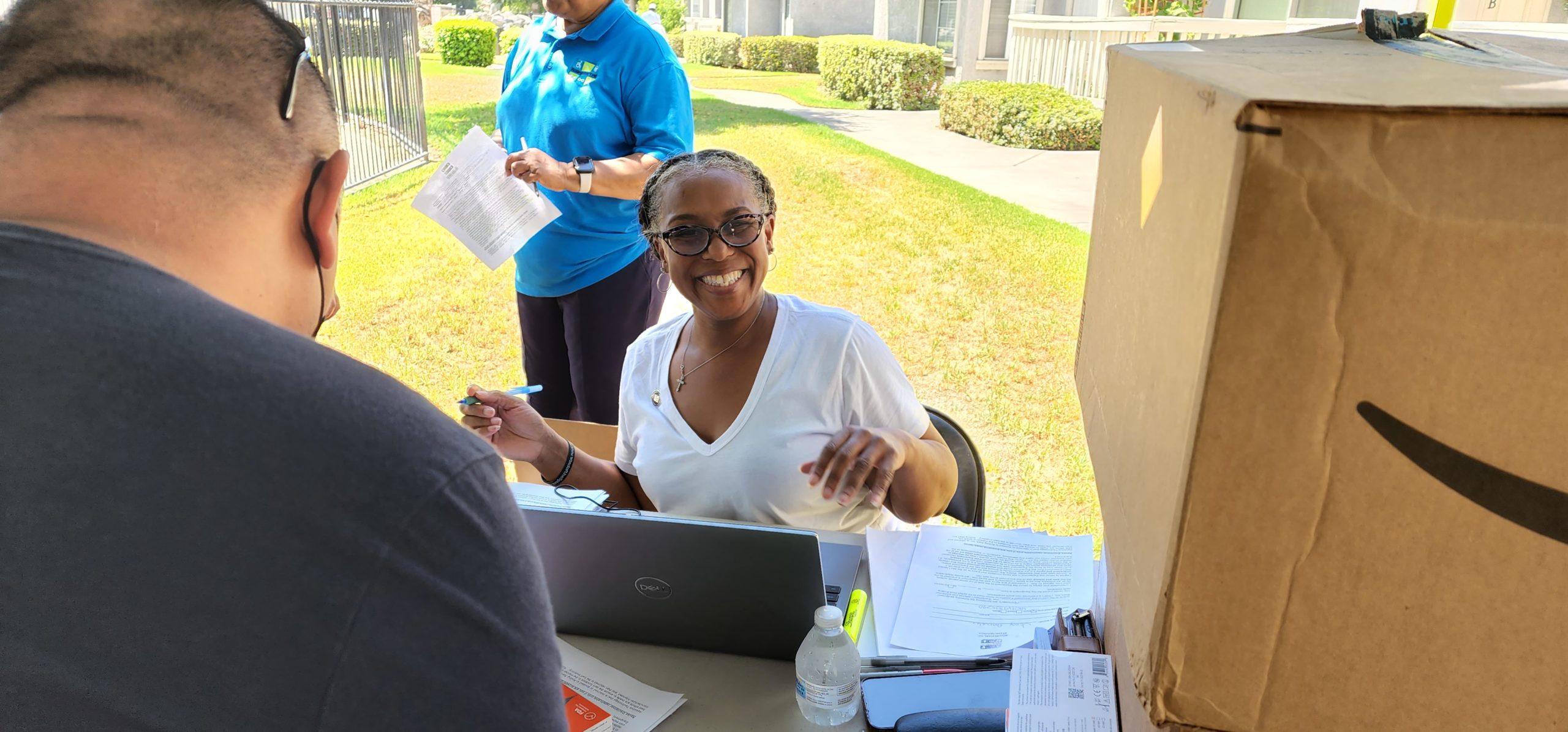 A rolling start staff member smiles for a photo inbetween entering information on a laptop at an outreach event.